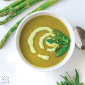 A bowl of vegan asparagus soup in a bowl with asparagus tips.