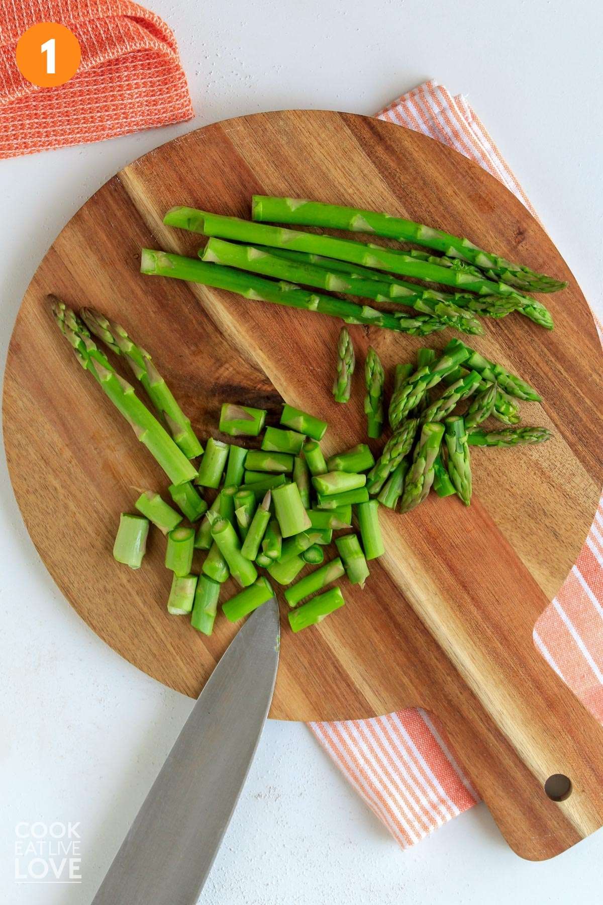 Cut asparagus on a cutting board with knife.