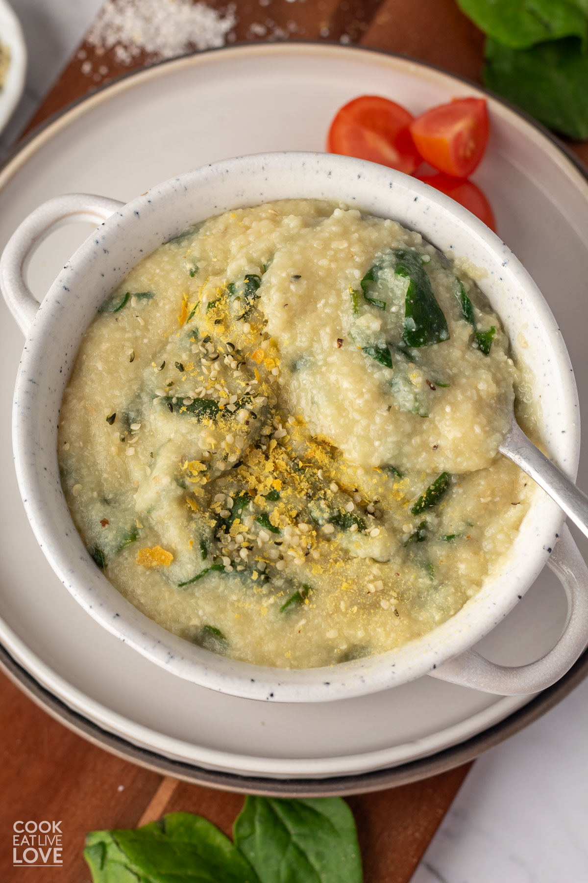 A bowl of vegan cheese grits in a bowl with a spoon.