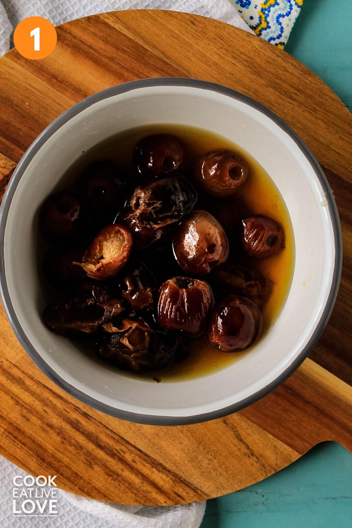 Bowl of dates in water on table.