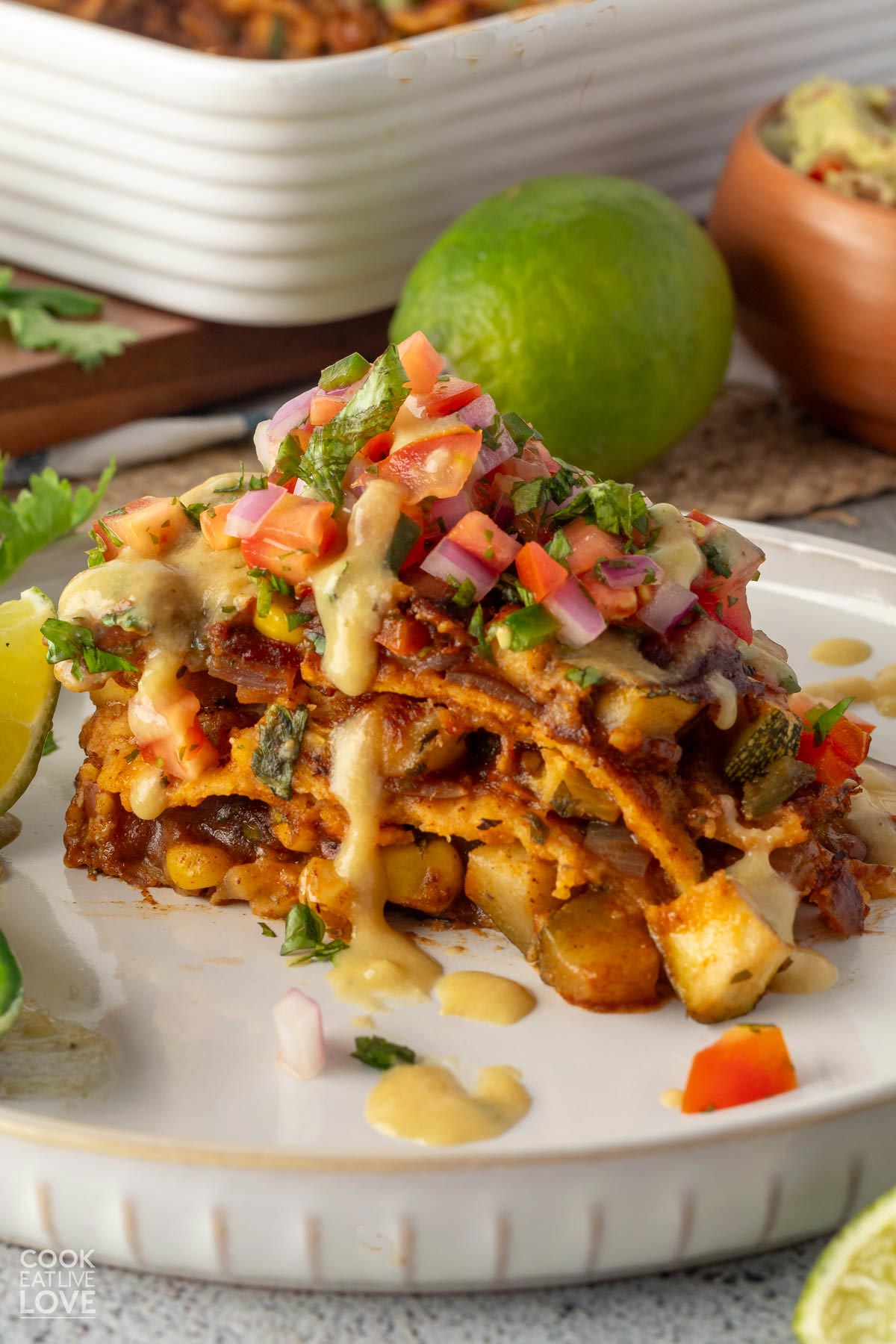 A serving of vegan enchilada casserole on a plate garnished with pico de gallo.