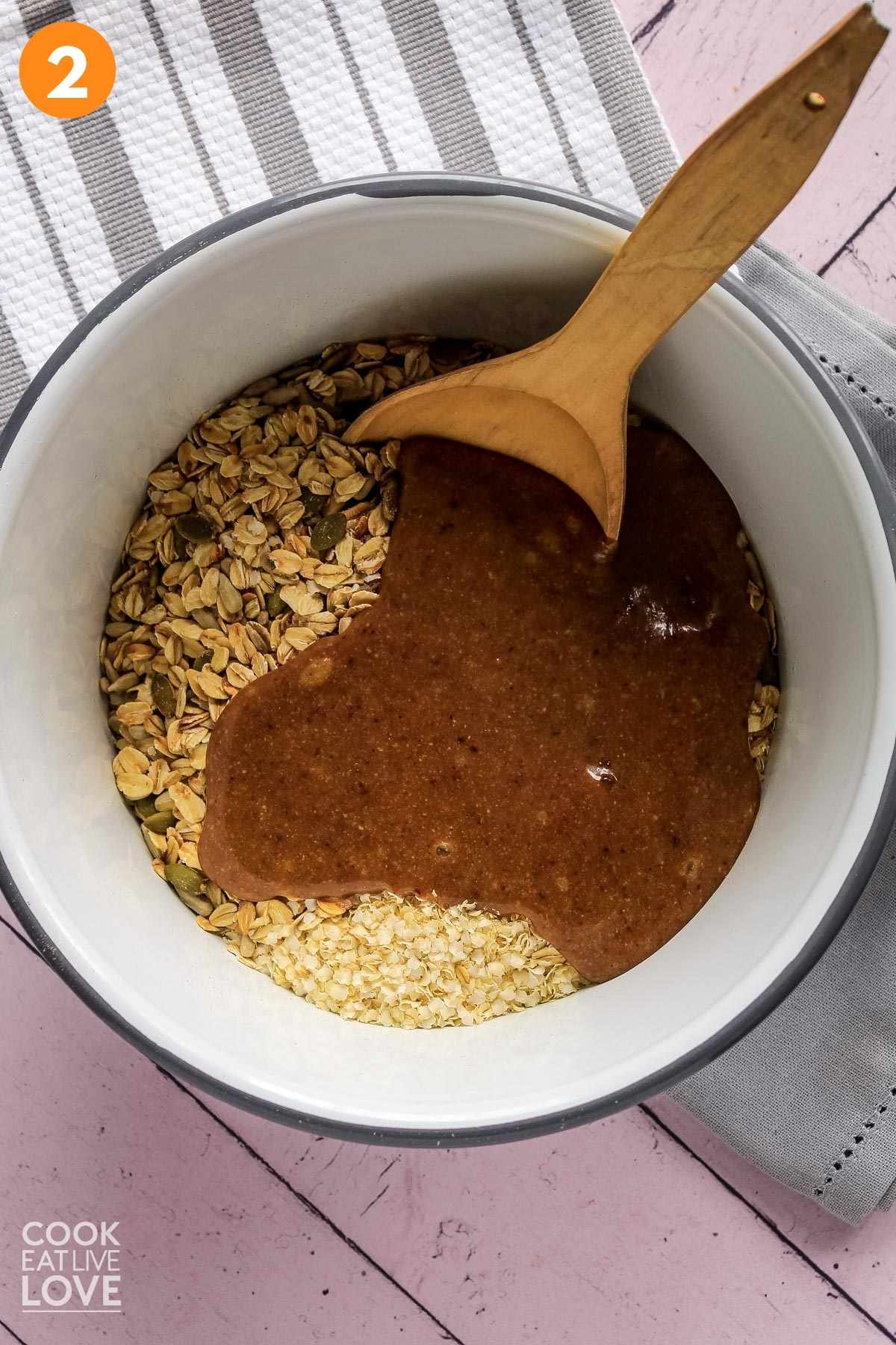 Oats and syrup in a white bowl with wooden spoon.