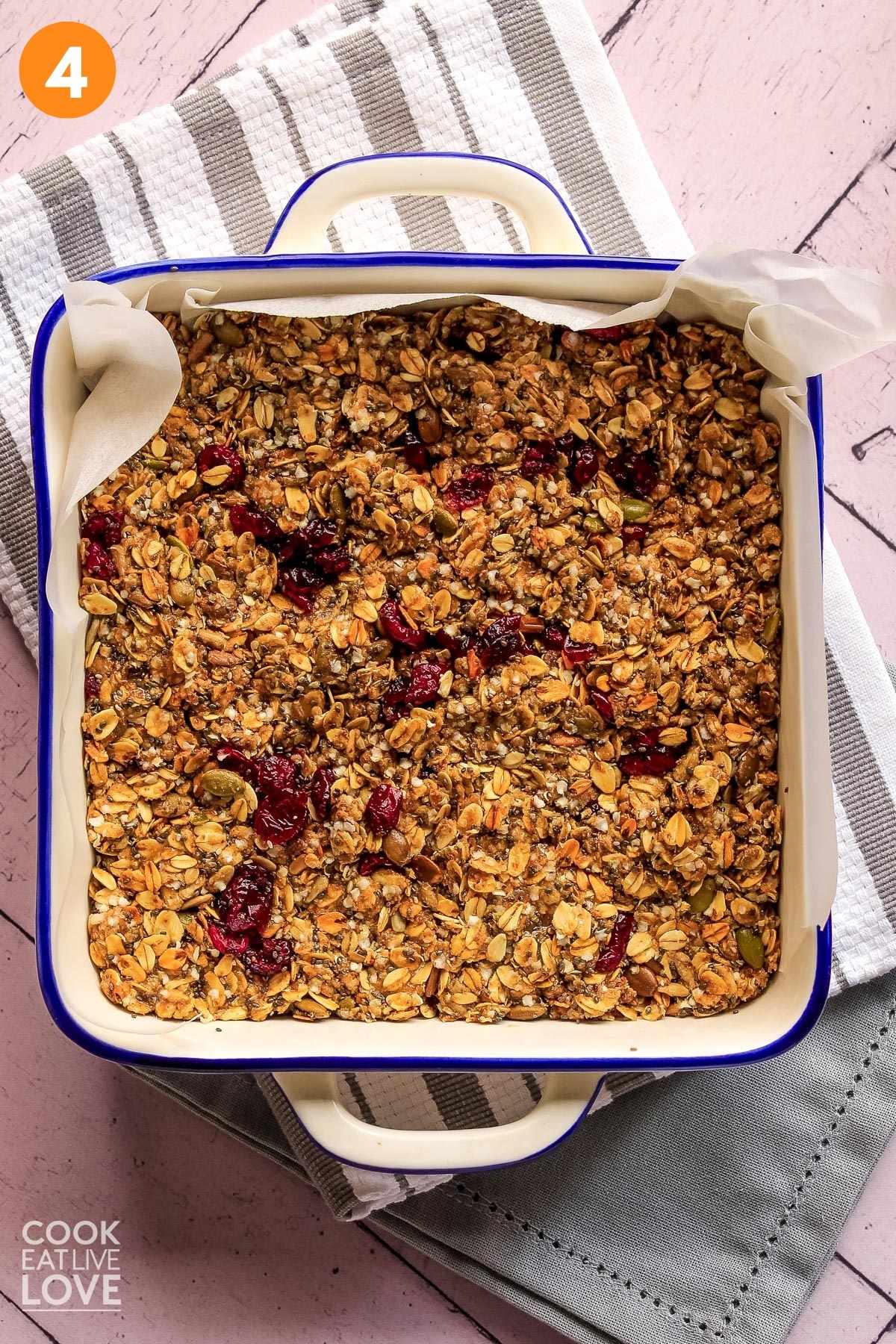 Vegan granola bar mixture is in square pan and pressed firmly down.