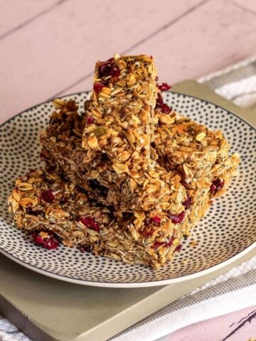 Vegan granola bars on a plate on a table with a pink background.