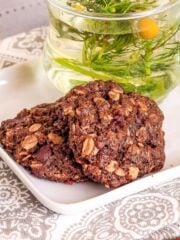 Two vegan chocolate oatmeal cookies ready to eat on plate.