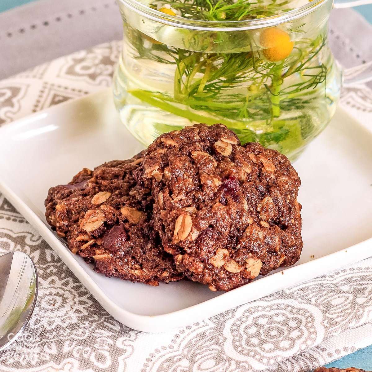 Two vegan chocolate oatmeal cookies ready to eat on plate.