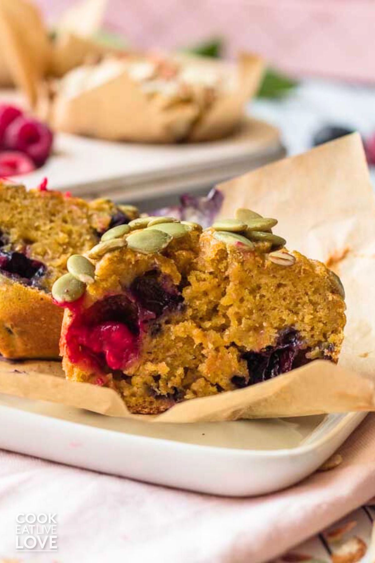 Pumpkin berry muffin on a plate with muffin pan behind with more