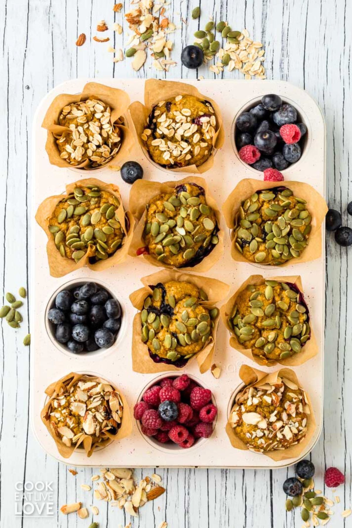 Eggless pumpkin muffins are in a muffin pan garnished with fresh berries.