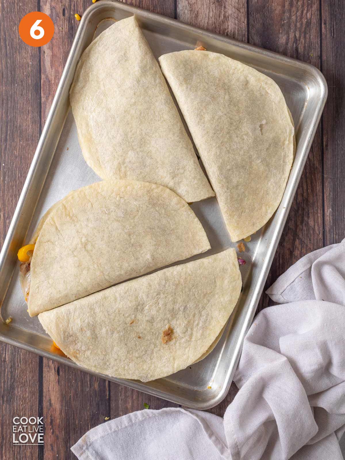 Folded quesadillas are ready on a baking sheet.
