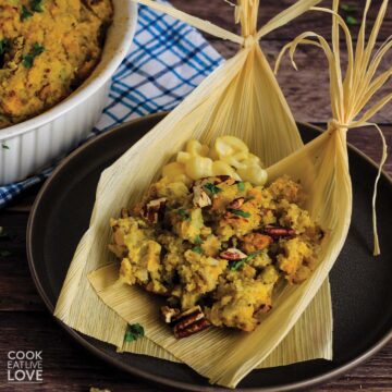 Corn husk on plate filled with vegetarian stuffing casserole with cornbread..