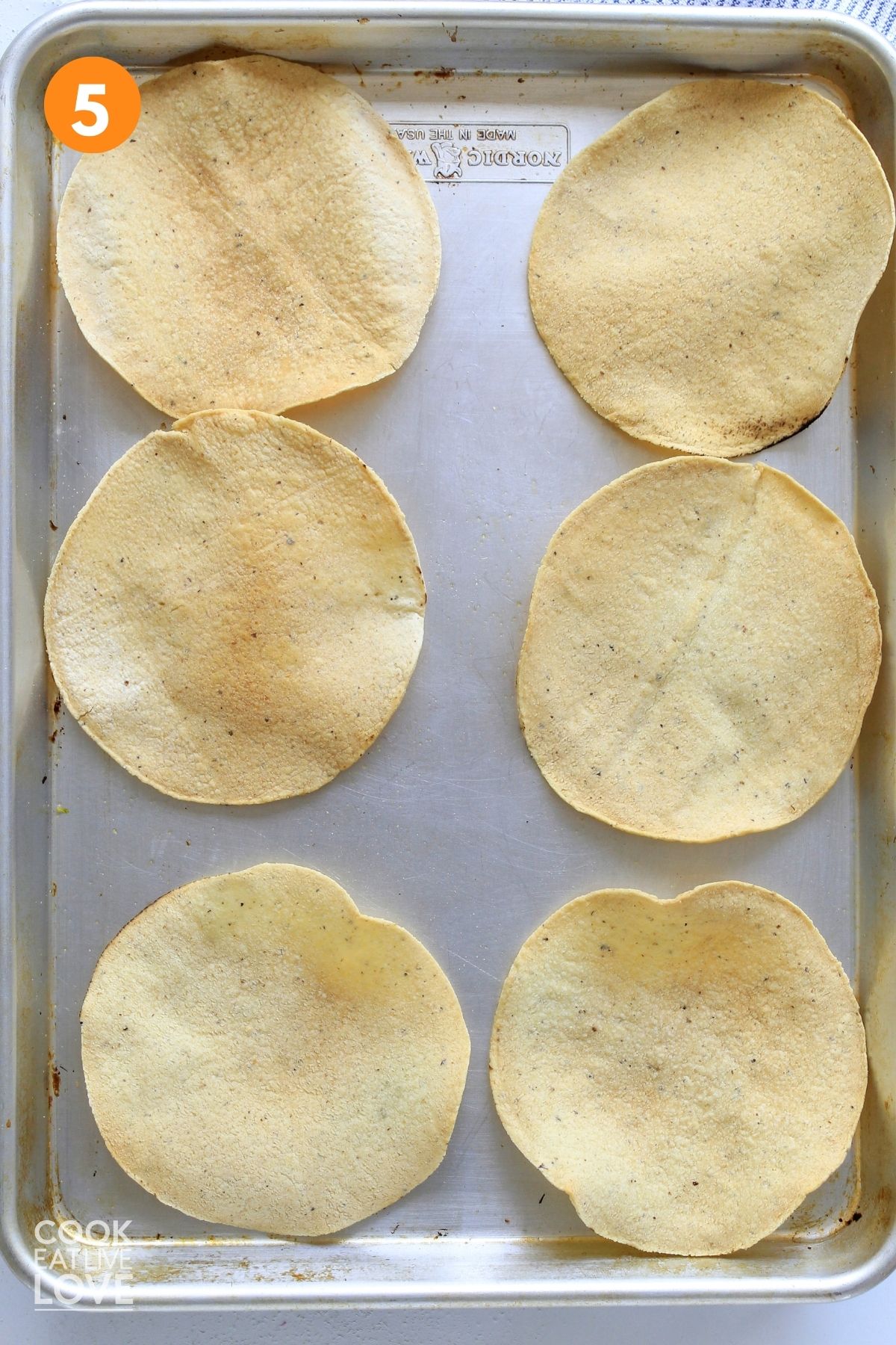Baked tostadas laid out on a baking sheet.