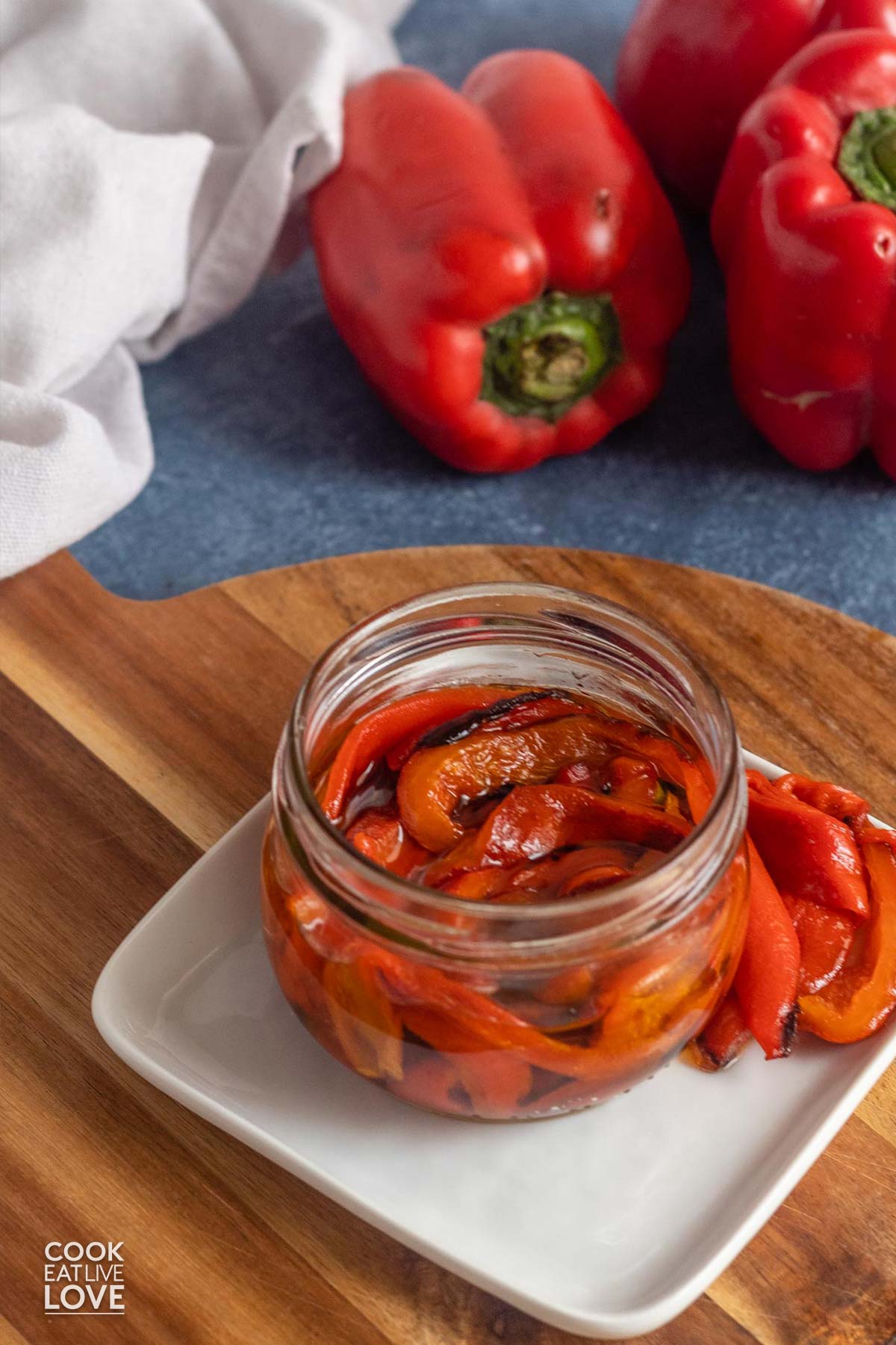 Air fryer roasted red peppers in a jar on a plate.