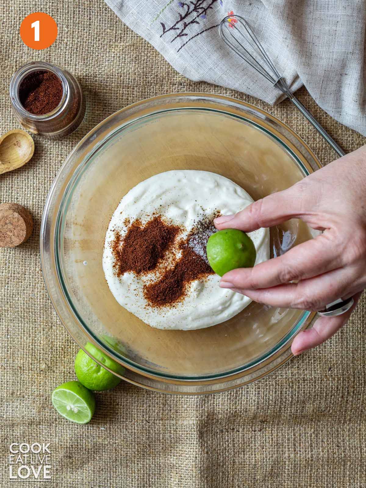 A hand squeezing a lime into the other chipotle sauce ingredients.