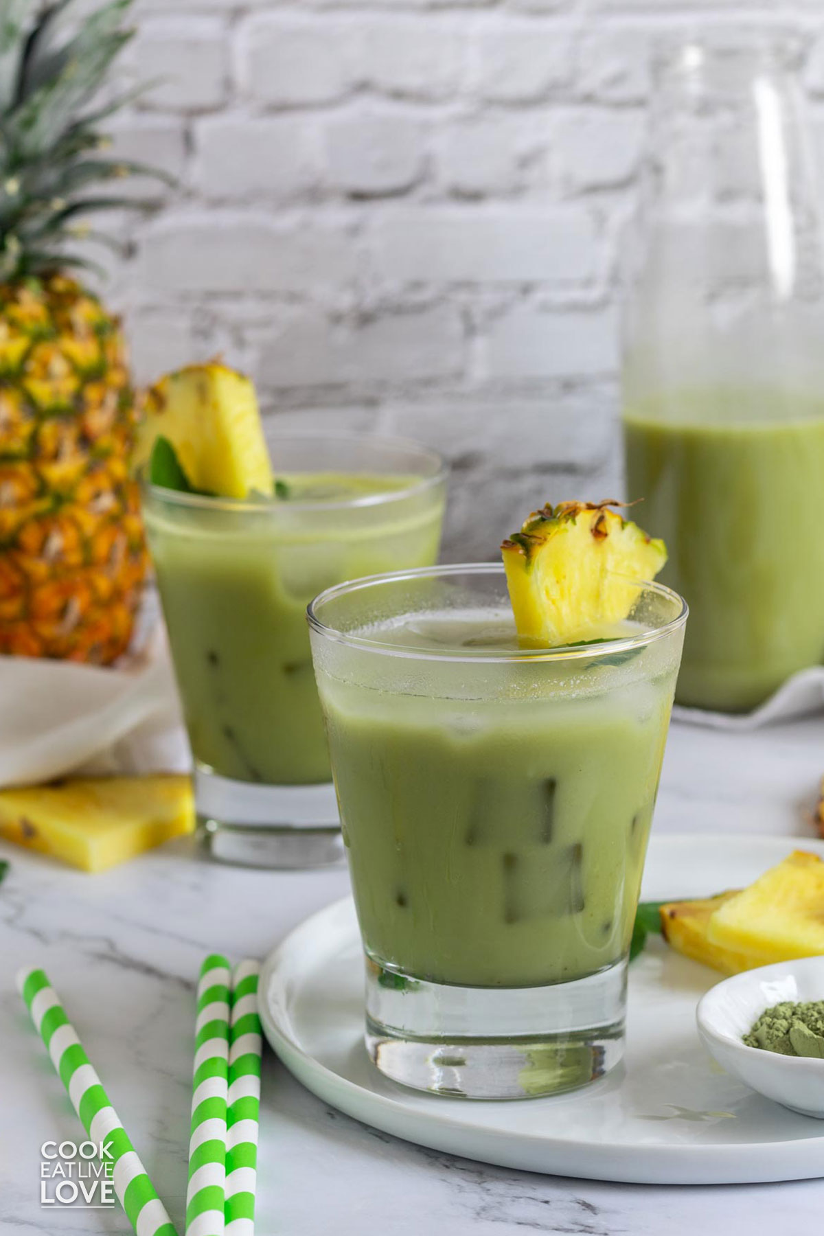 Glasses of pineapple matcha drink on the table with pineapple half.
