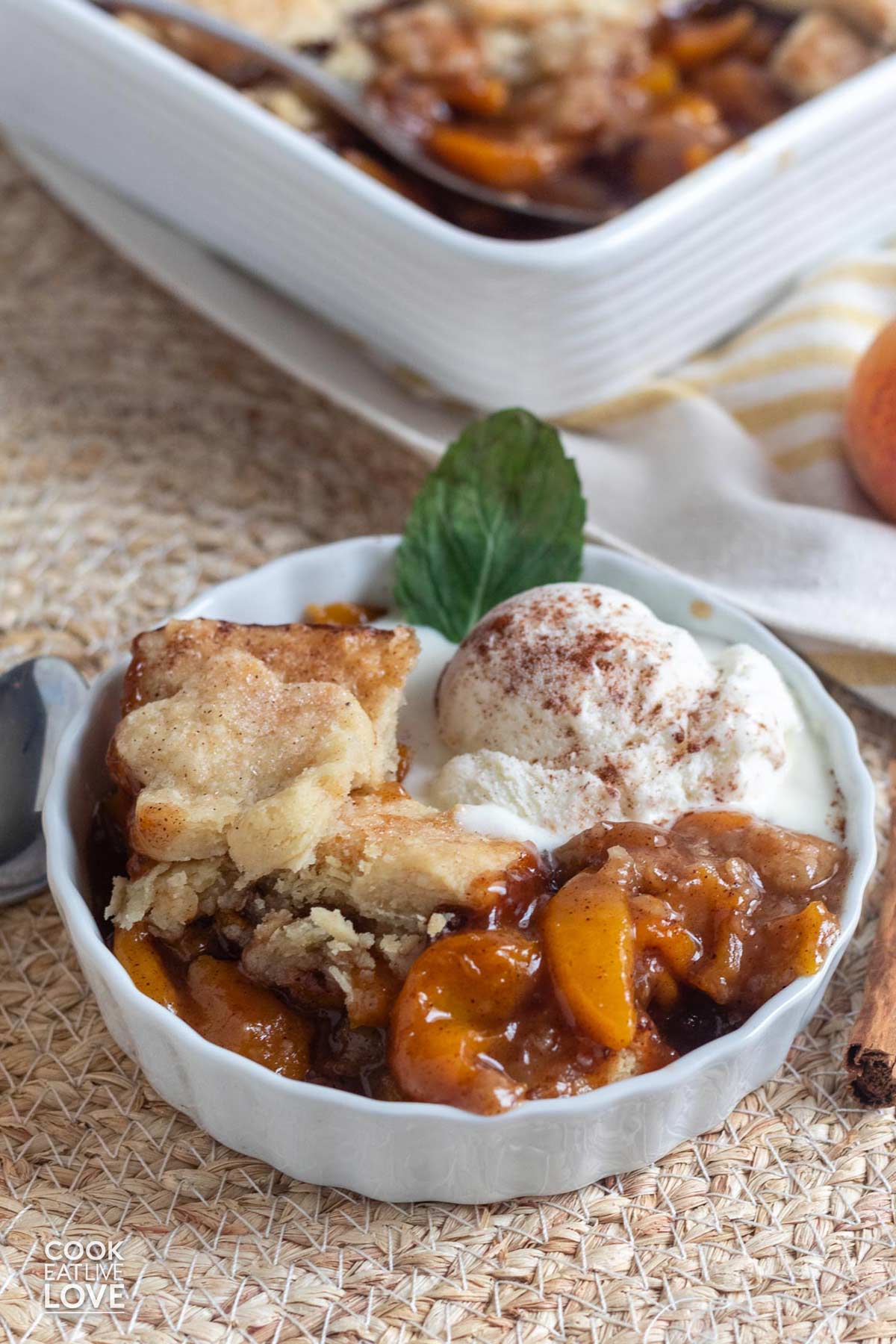 A close up of vegan peach cobbler with ice cream in a small dish.
