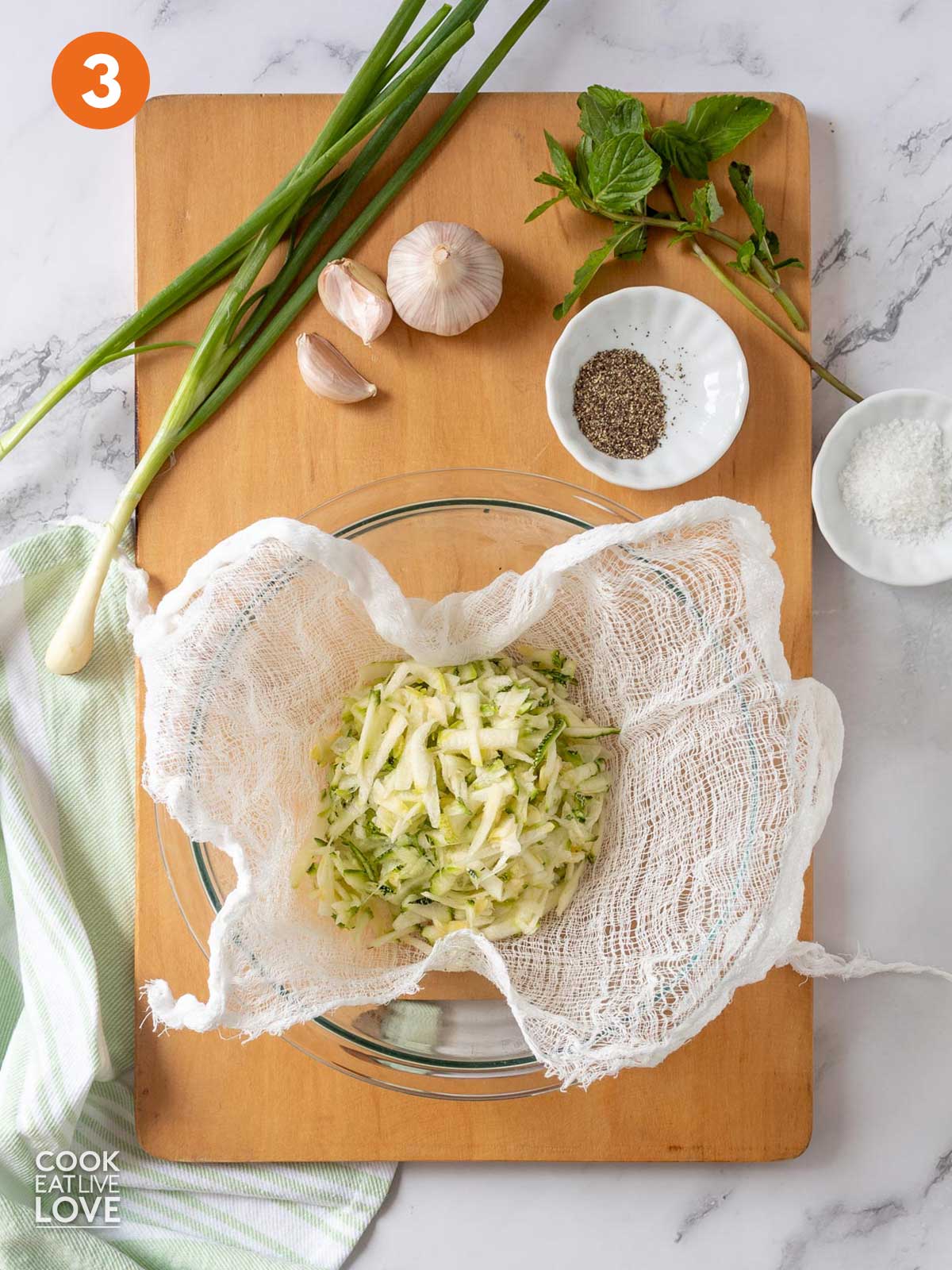 Grated zucchini inside cheesecloth lined bowl.