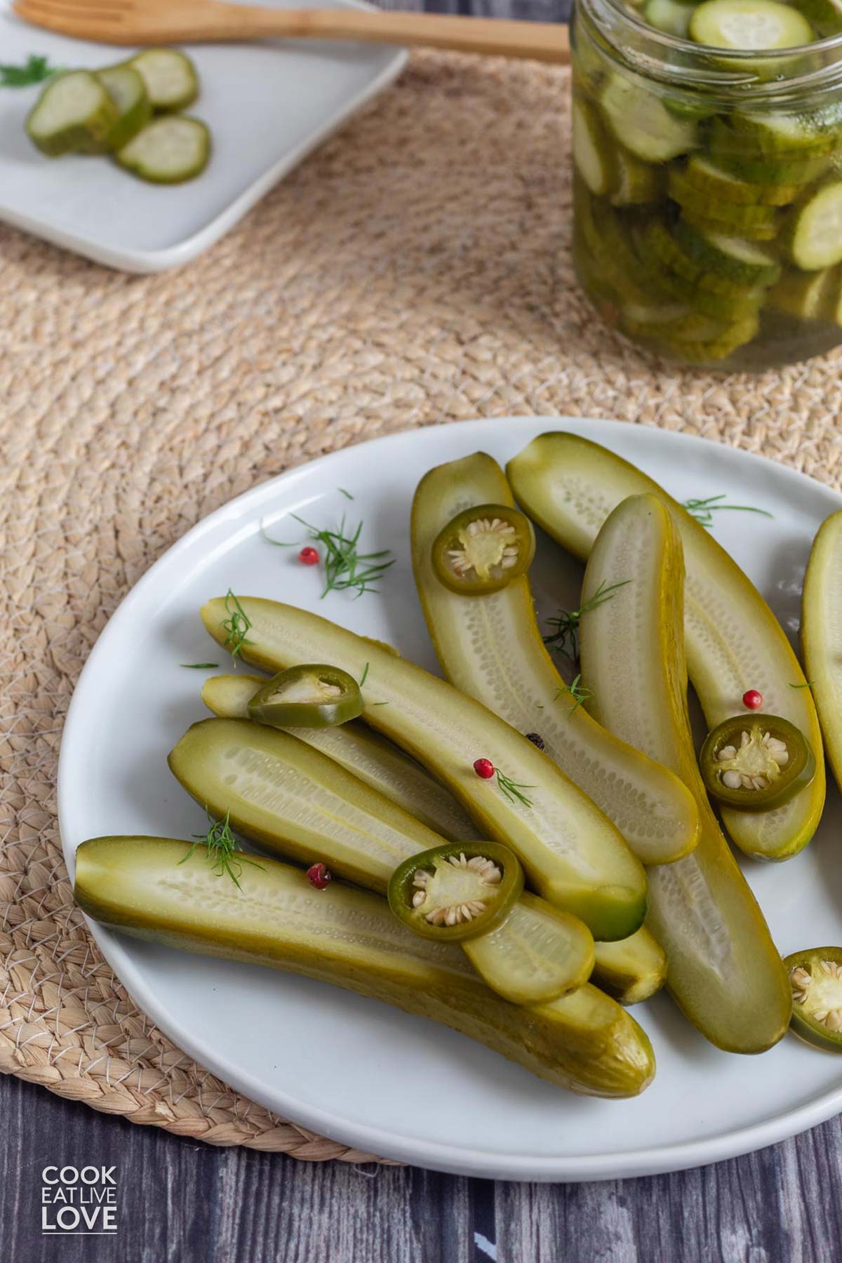 A plate of small batch refrigerator pickles on a wicker mat on the table.