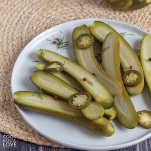 Refrigerator dill pickle halves on a plate with slices of jalapenos.