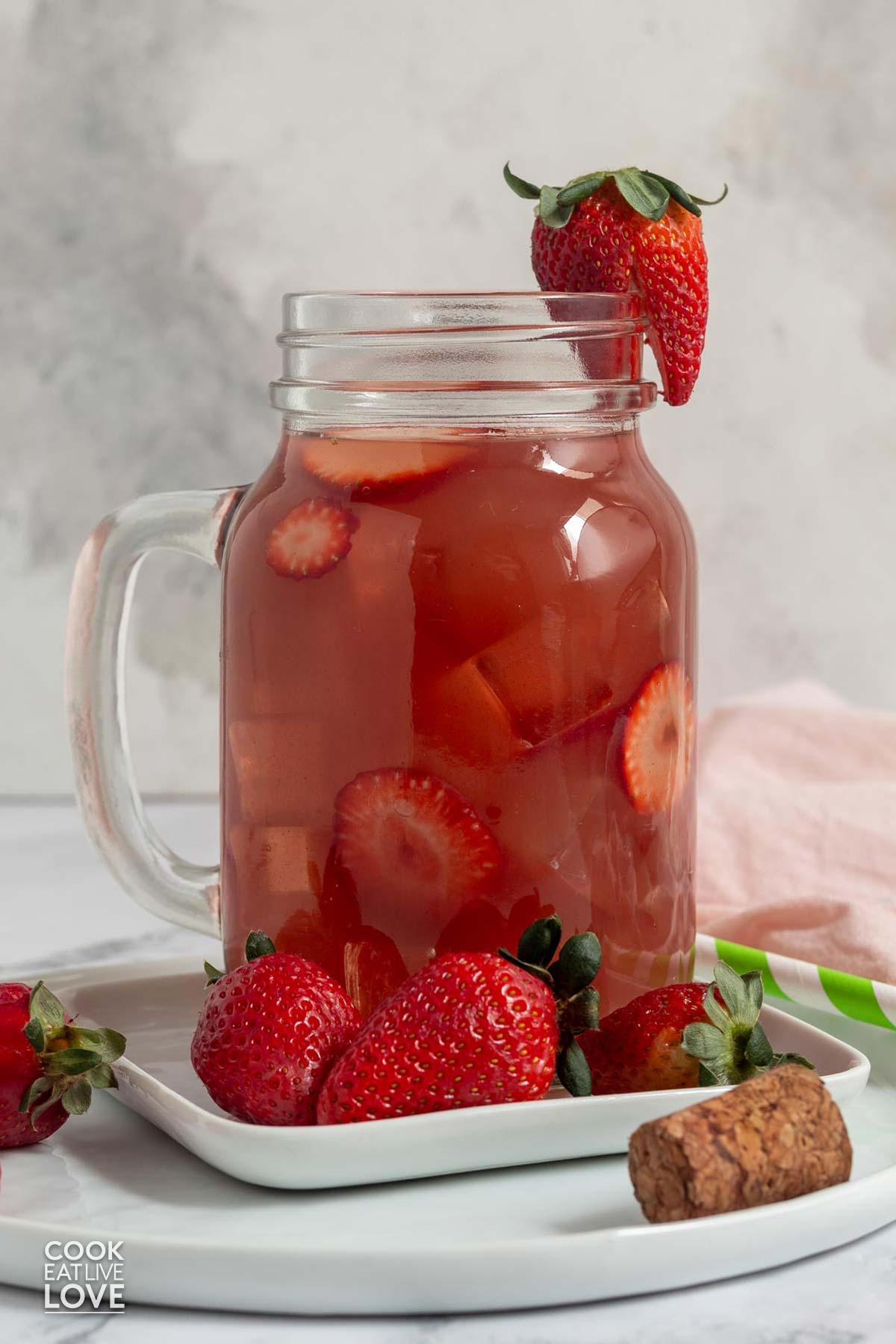 A jar of strawberry acai refresher on the table with fresh berries.