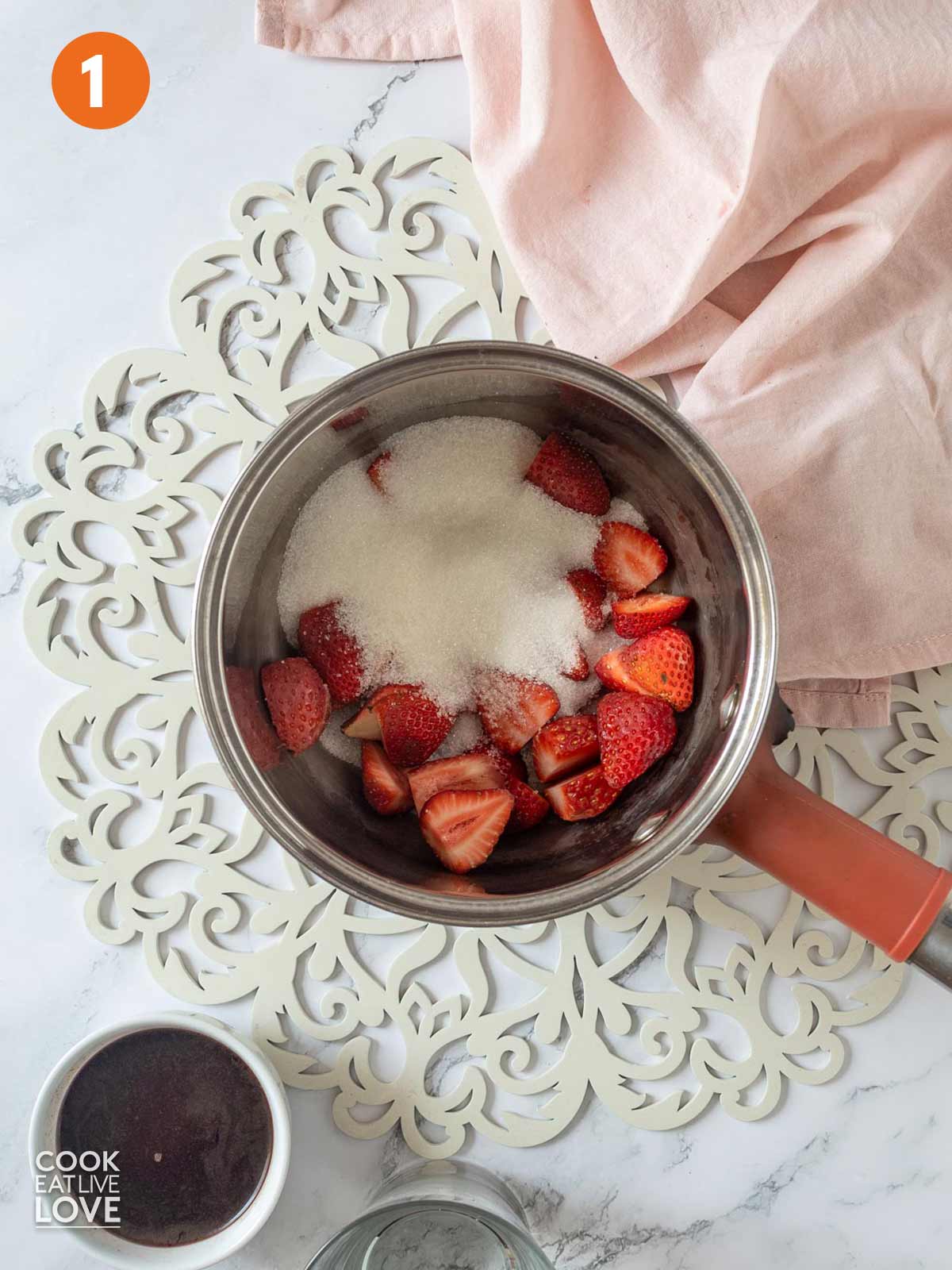 Strawberry in a pot with sugar added and the acai in the bowl next to it.