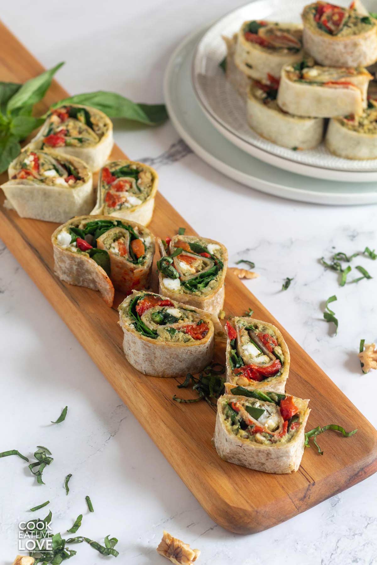 Vegan pinwheels with hummus and cheese rolled up and sliced on a platter.