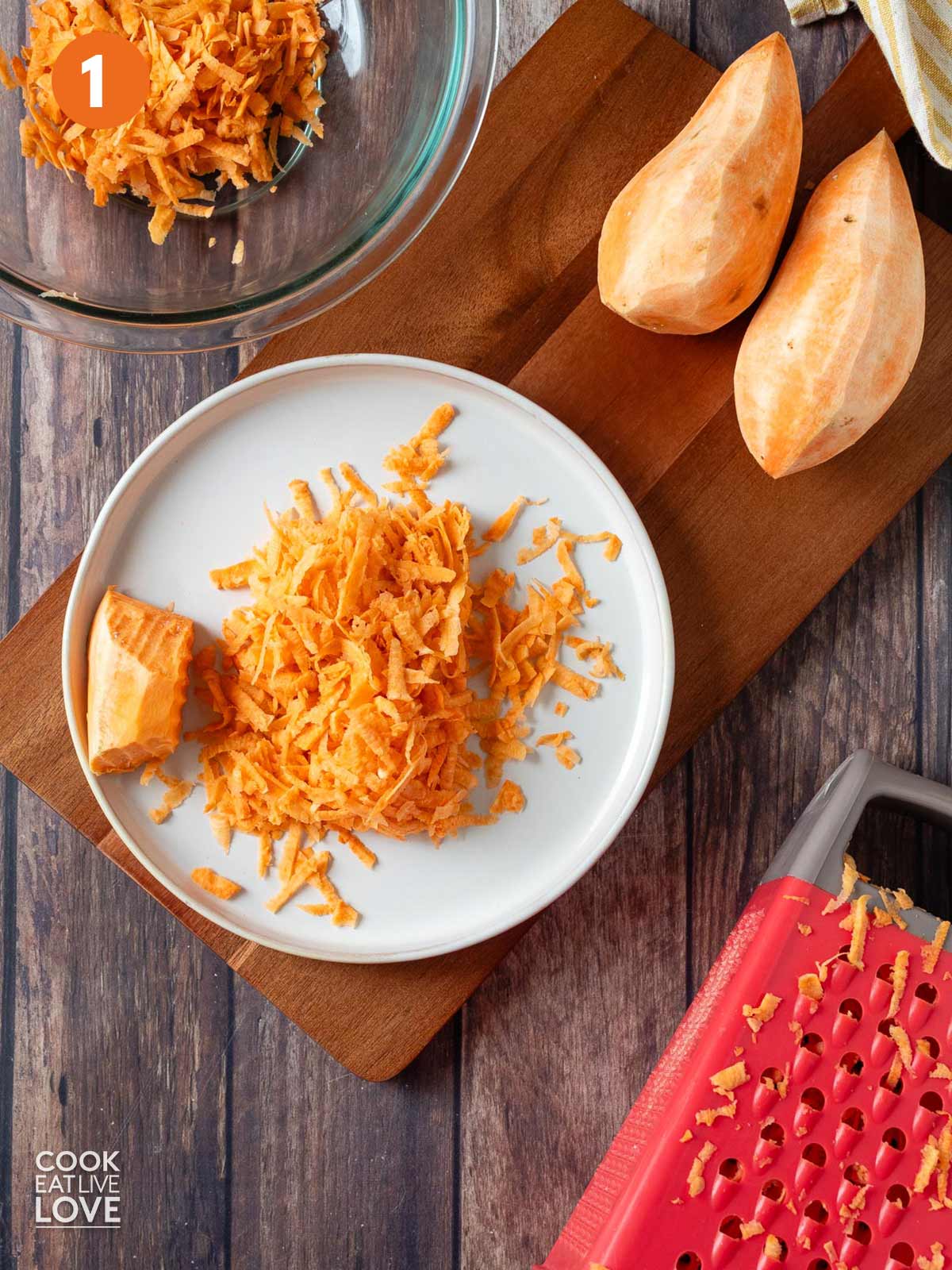 Shredded sweet potatoes on a white plate with a box grater in the corner.
