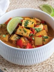 A bowl of vegetarian Thai yellow curry with tofu with fresh lime.