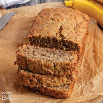 Banana bread no butter on the table with a few slices cut in front of the full loaf.