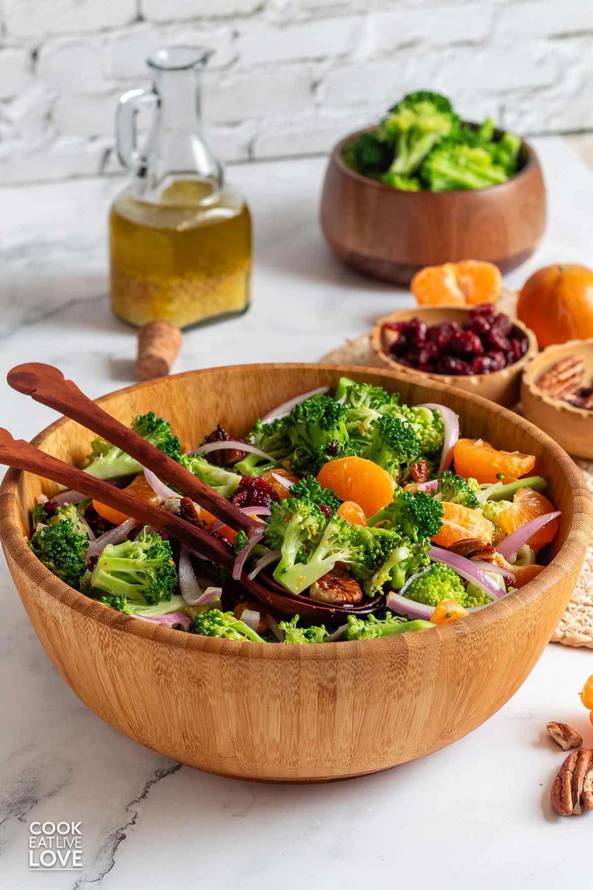 Cranberry broccoli salad in a bowl on the table with serving spoons on top.