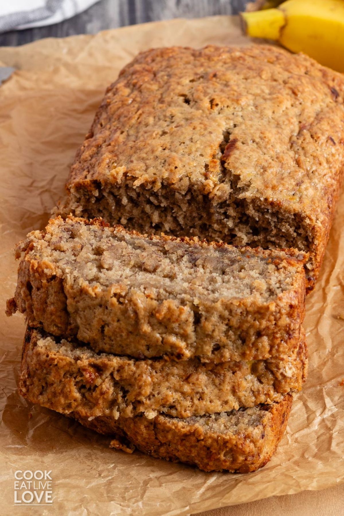 A loaf of no butter banana bread on the table with a few slices in front.