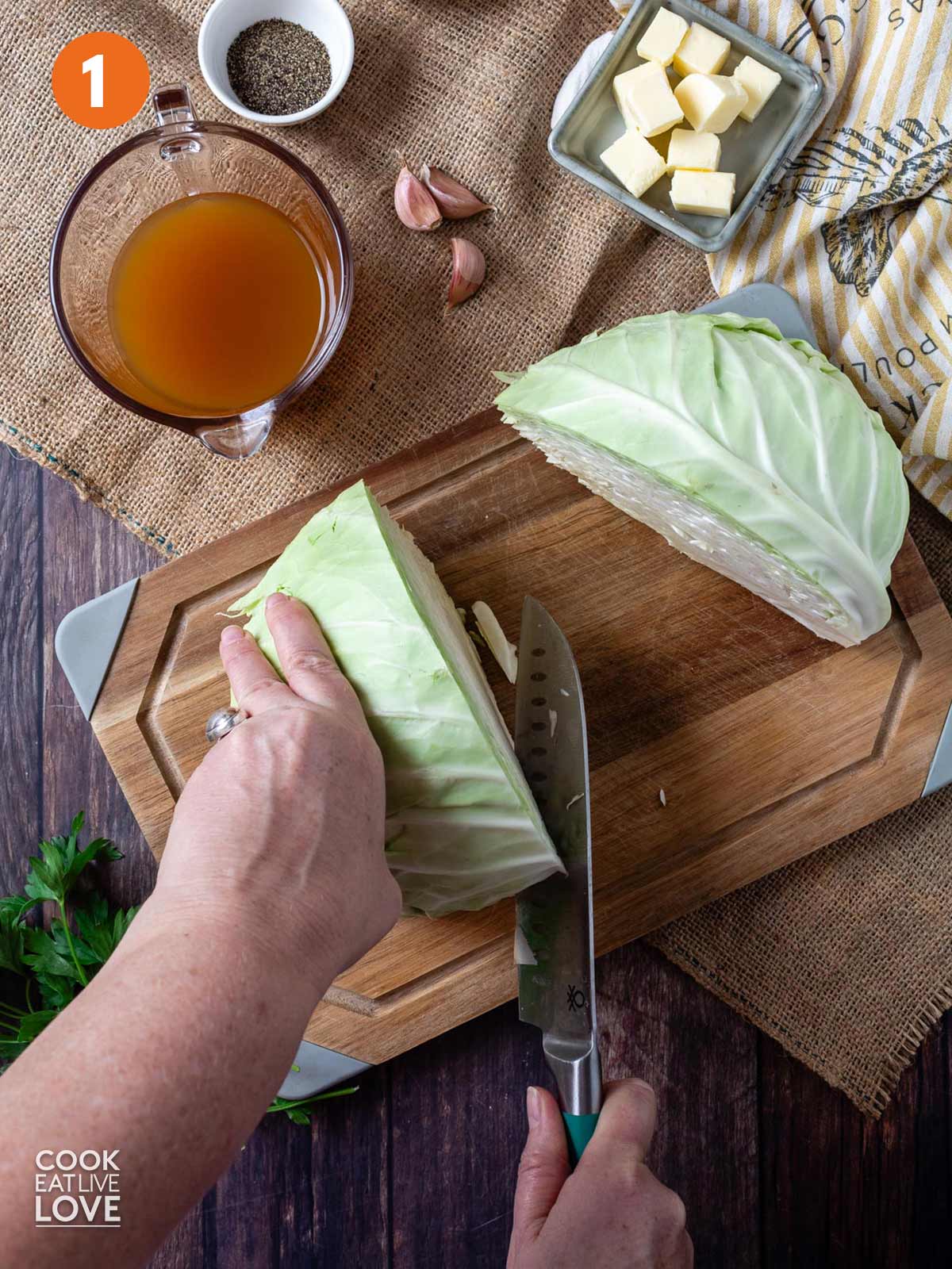 Head of cabbage cut in half with a knife on a cutting board.
