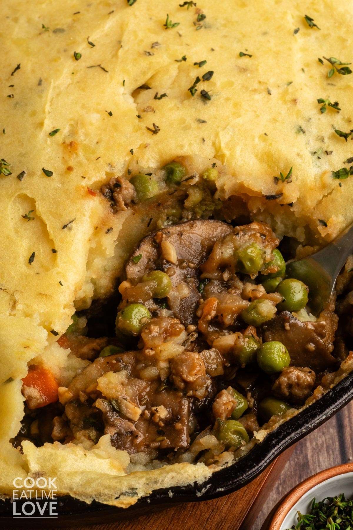 A close up of beyond meat shepherd's pie on the table with a portion missing and you can see the inside mixture topped with mashed potatoes.