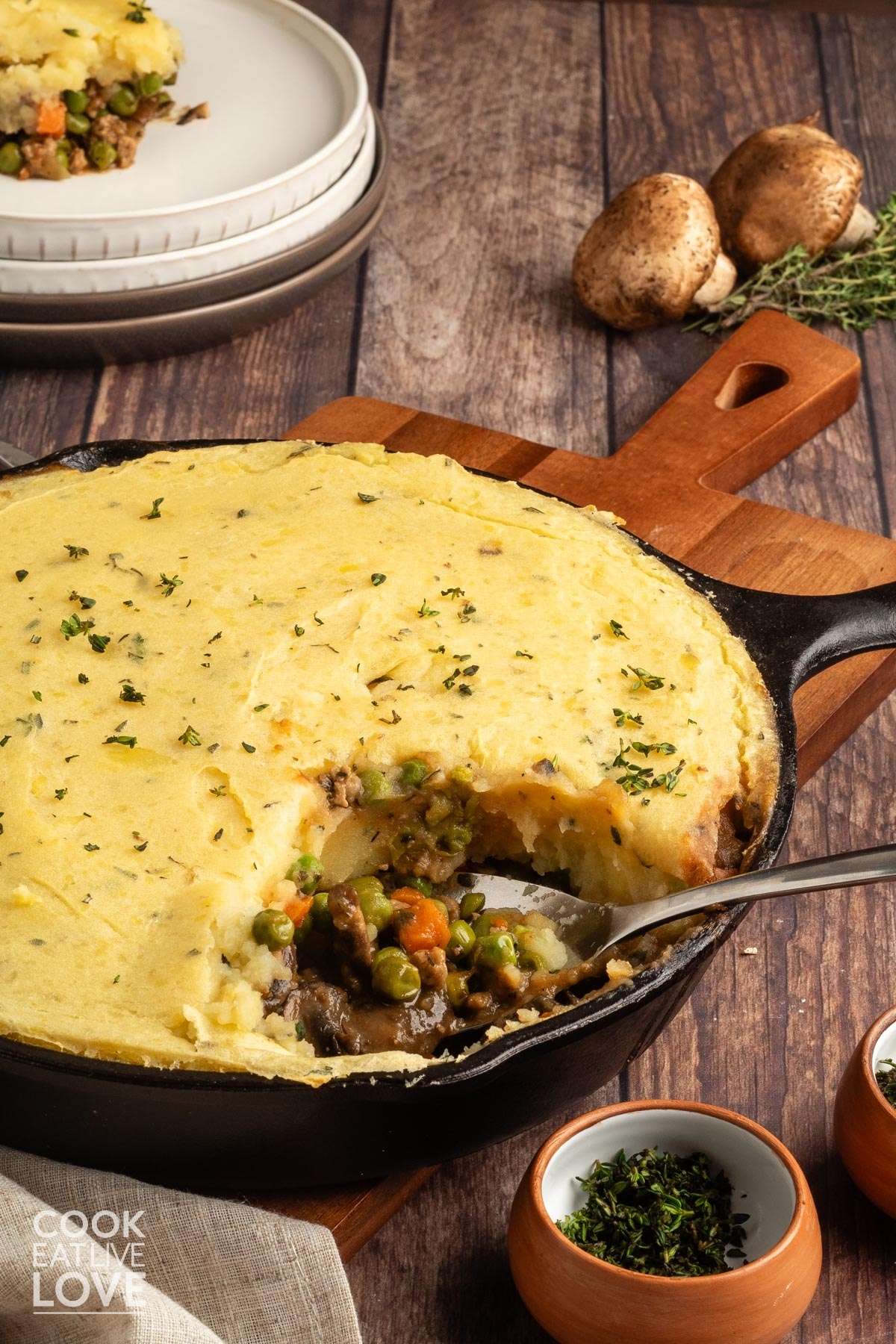 Mushroom shepherd's pie in a skillet on the table with a spoon and some scooped out.