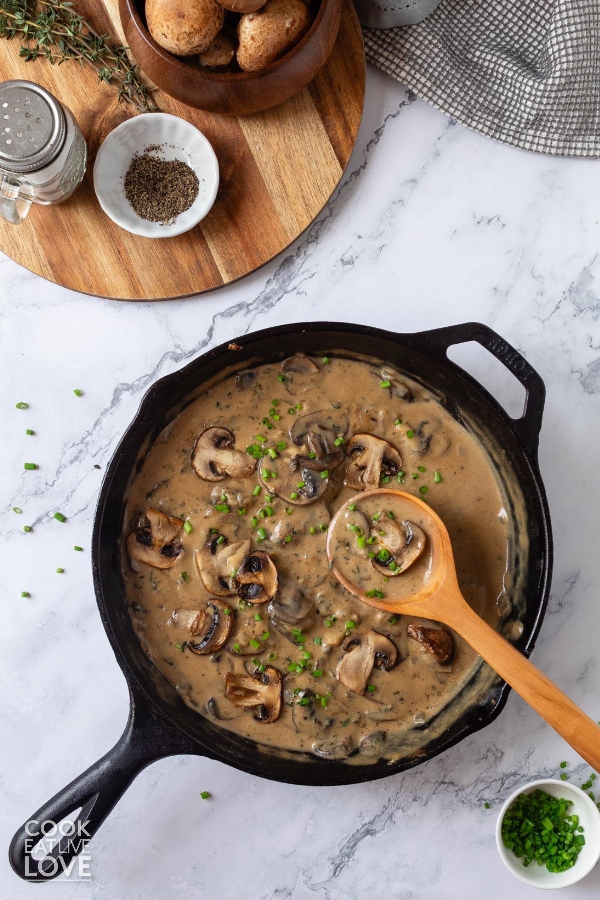 A skillet of vegan mushroom sauce on the table with a bowl of brown mushrooms. 