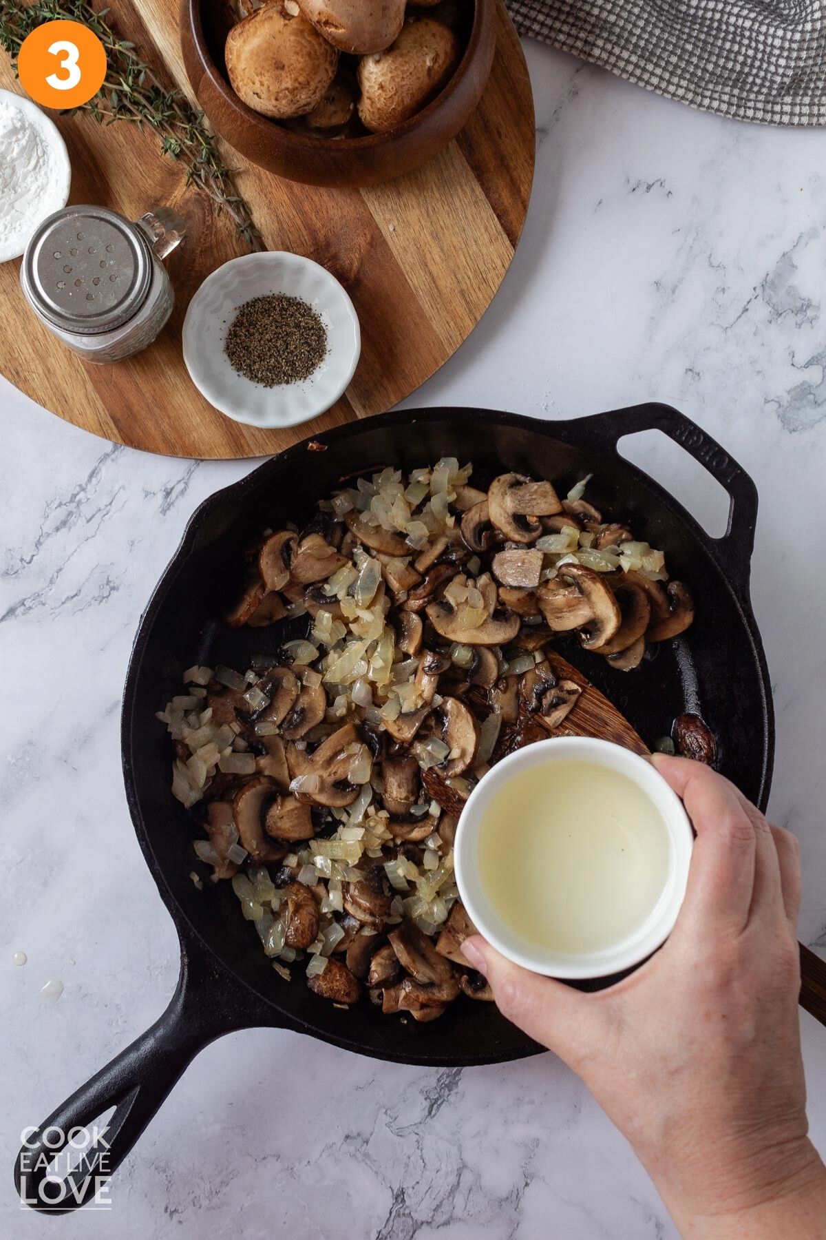 Adding the wine to the skillet of mushrooms and aromatics.