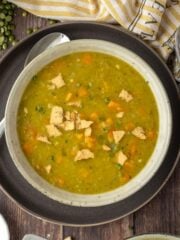 Close-up overhead shot of instant pot split pea soup in a bowl on a plate with a spoon on the plate.