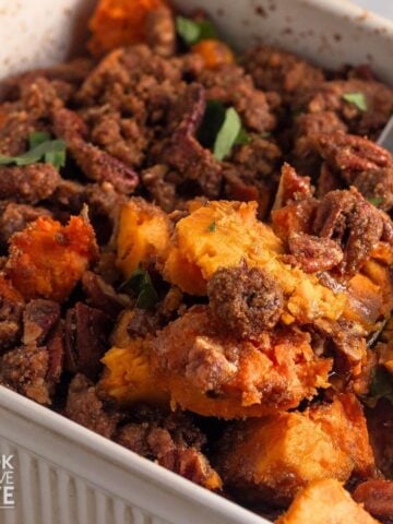 A spoon lifting up a portion of old-fashioned sweet potato casserole from the baking dish.