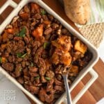 A casserole dish of old-fashioned sweet potato casserole with a spoon resting in it.