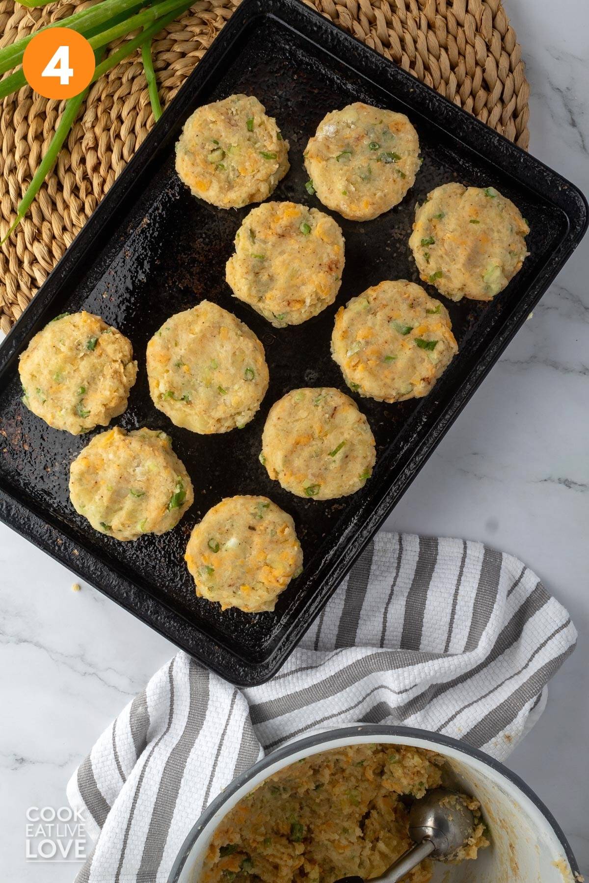 Uncooked formed patties on a black baking sheet.
