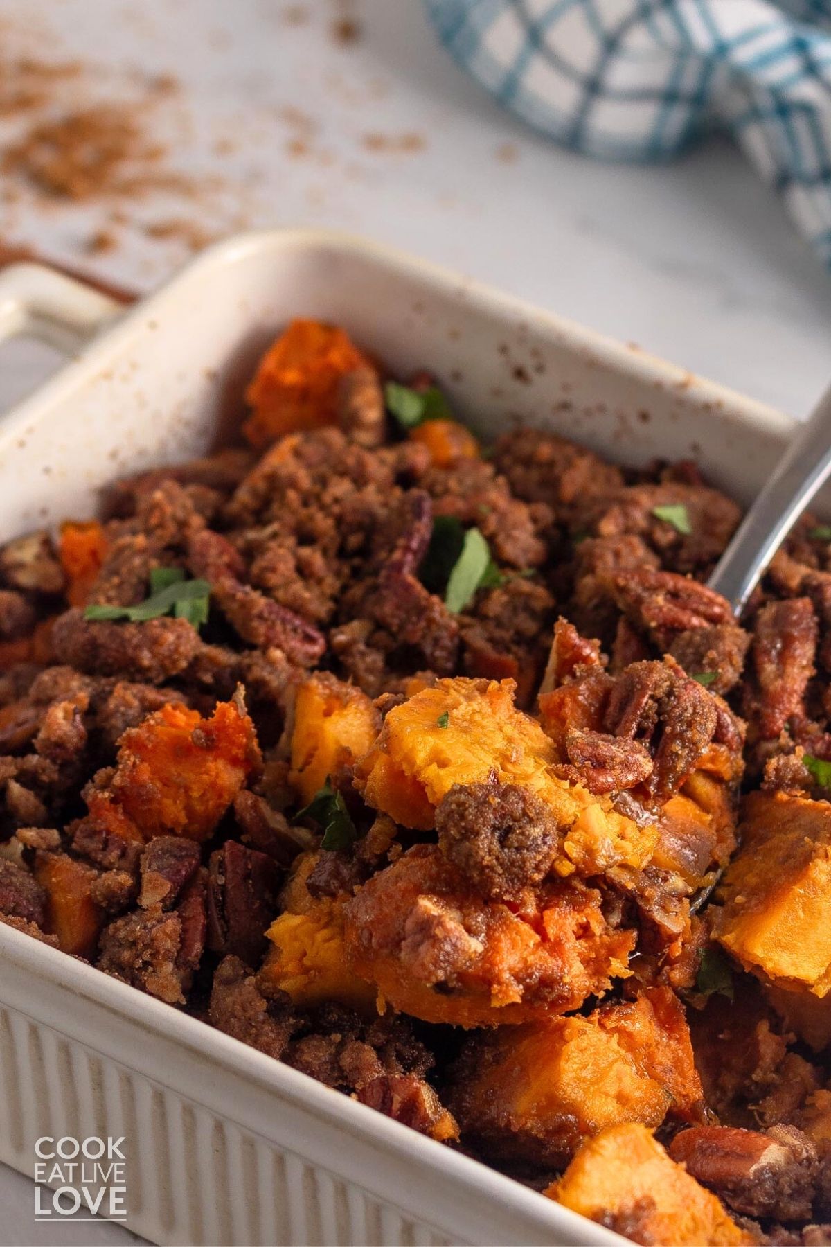 Old-fashioned sweet potato casserole in a white dish with a spoon lifting up a serving. 