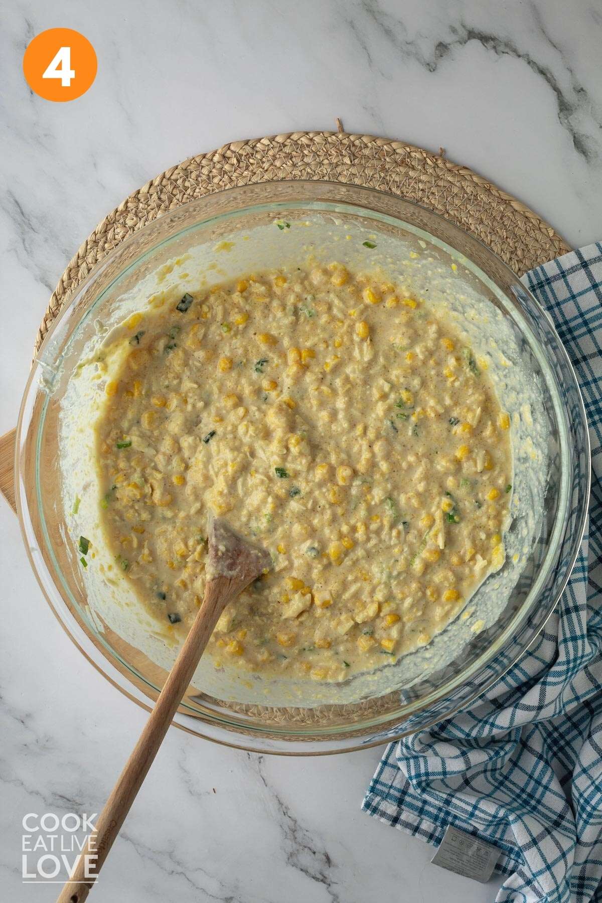 Flour, cornmeal, sugar, baking powder, vegan yogurt, cheese, milk, salt, pepper, drained corn, pureed corn, and cooked green onions in a large bowl after being mixed with a wooden spoon in it.