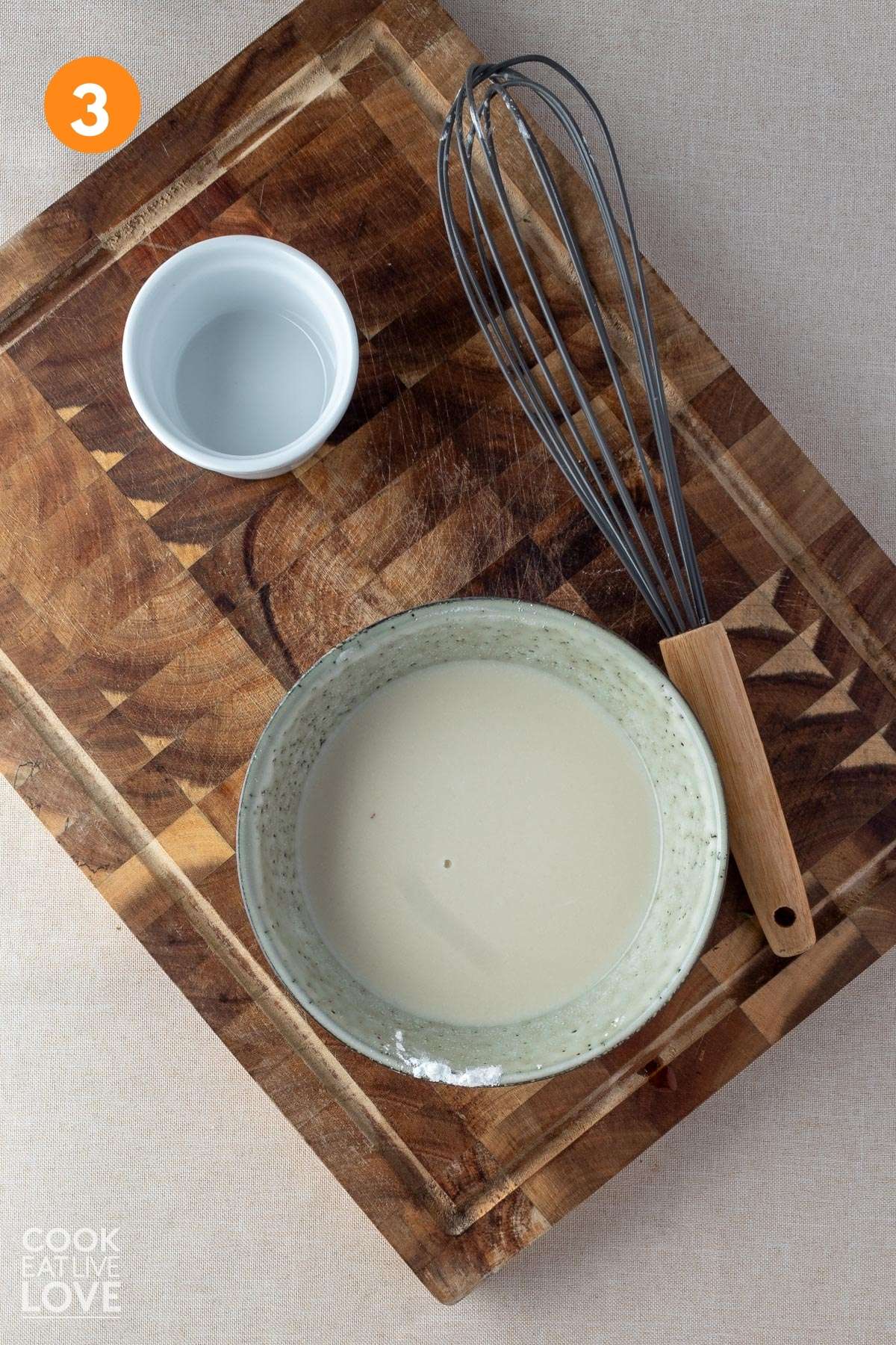 Cornstarch slurry mixed in small bowl on a cutting board.