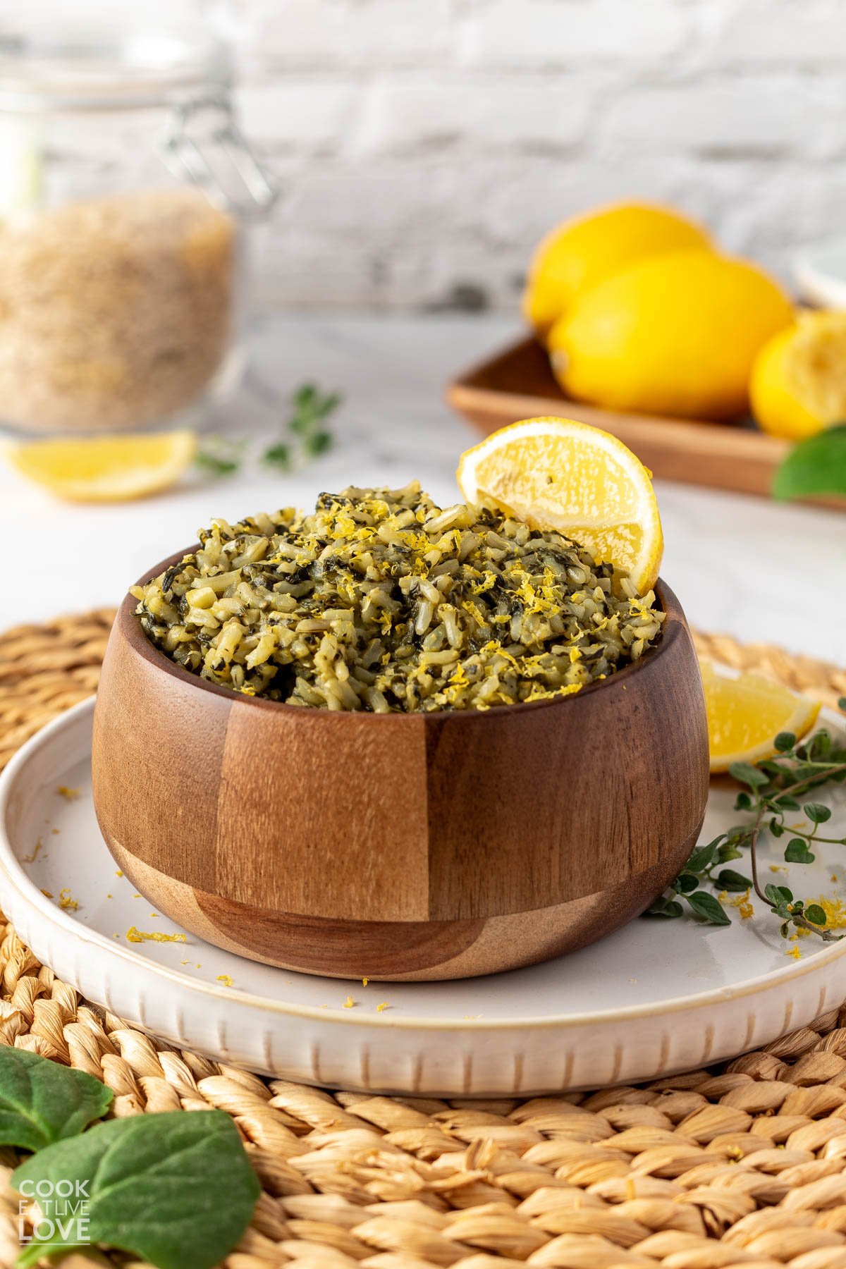 A wooden bowl filled with spinach mediterranean rice on a wicker placemat.