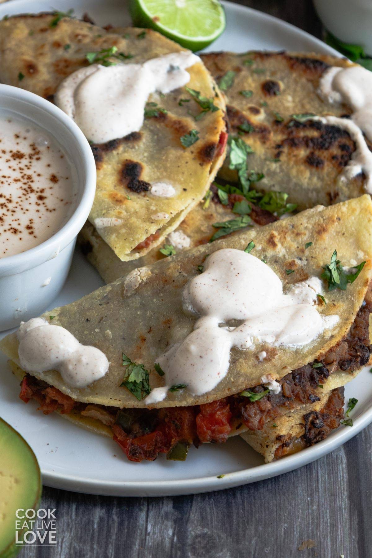 Black bean tacos on a plate with creamy white sauce on top.