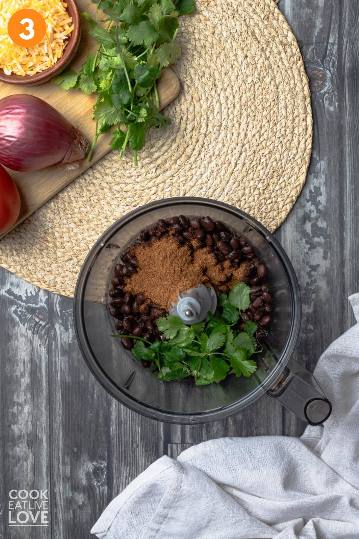 Black beans, seasonings, and cilantro in a food processor.