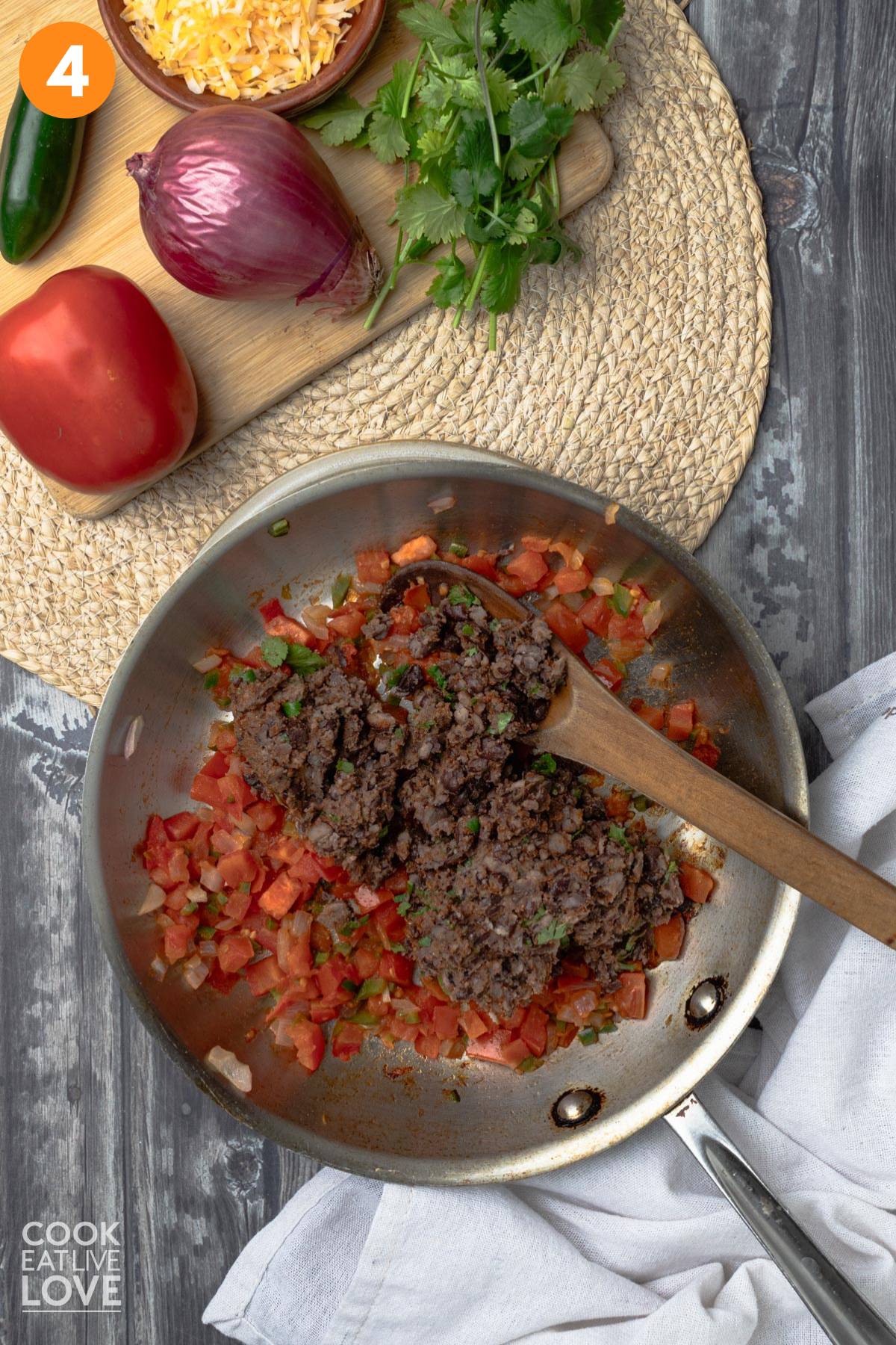 Black beans added to skillet of cooked tomatoes.