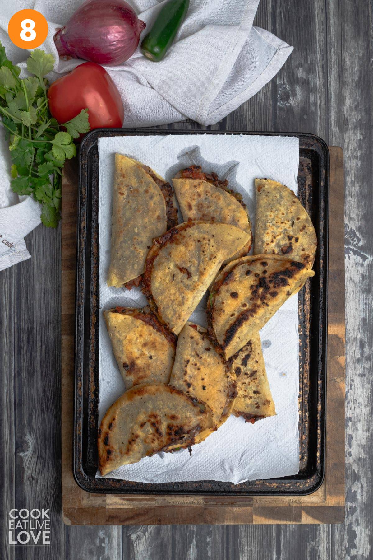 Crispy black bean tacos on a baking pan with a paper towel.