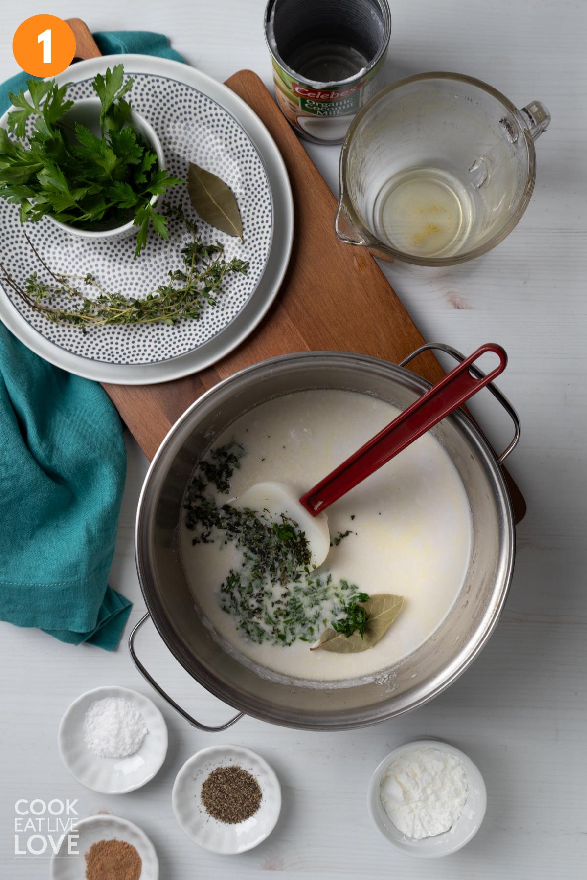 Milk and herbs added to a saucepan with a spatula in the pan.