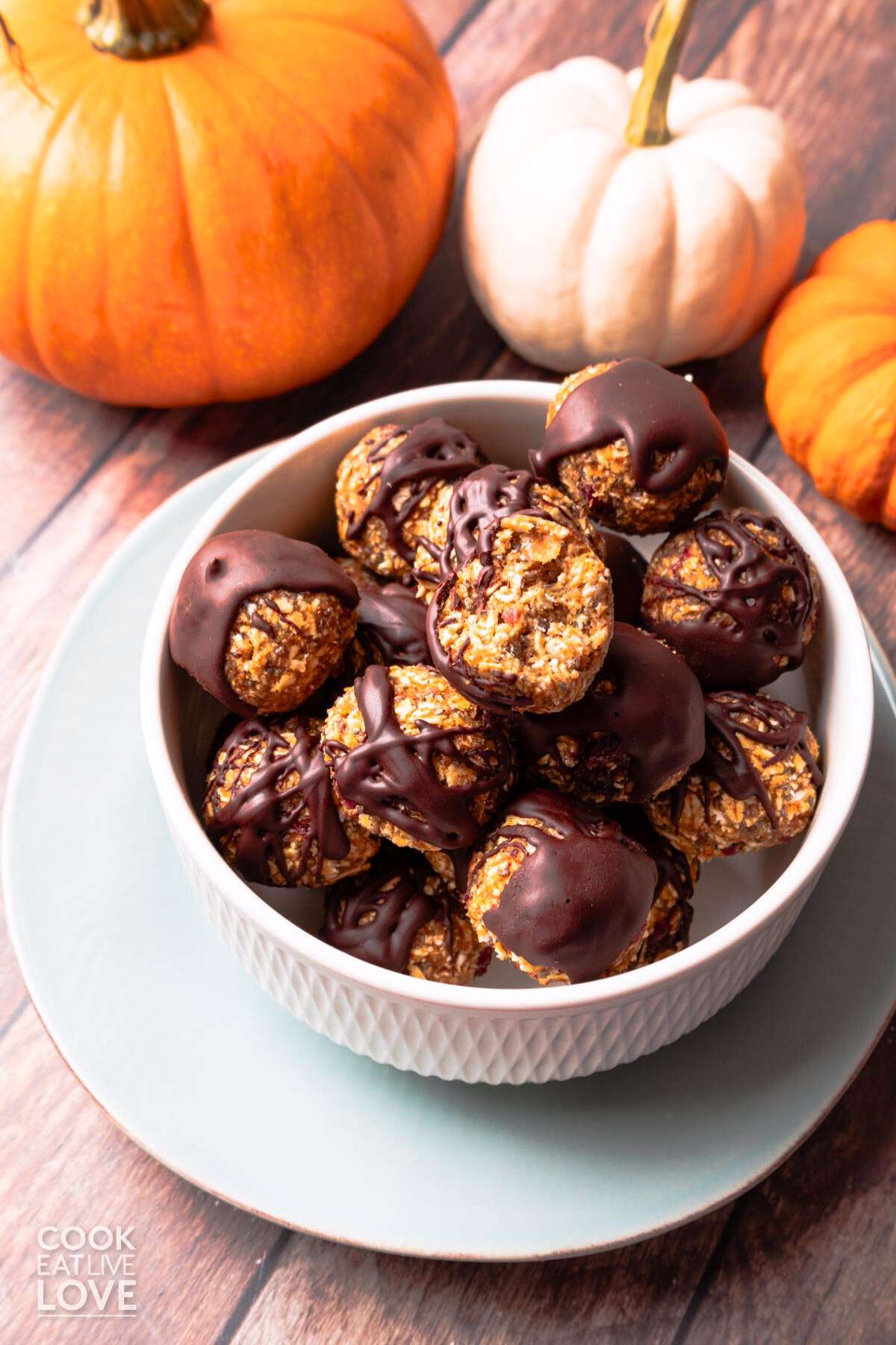 A bowl of pumpkin bites on the table with three small pumpkins in the background.