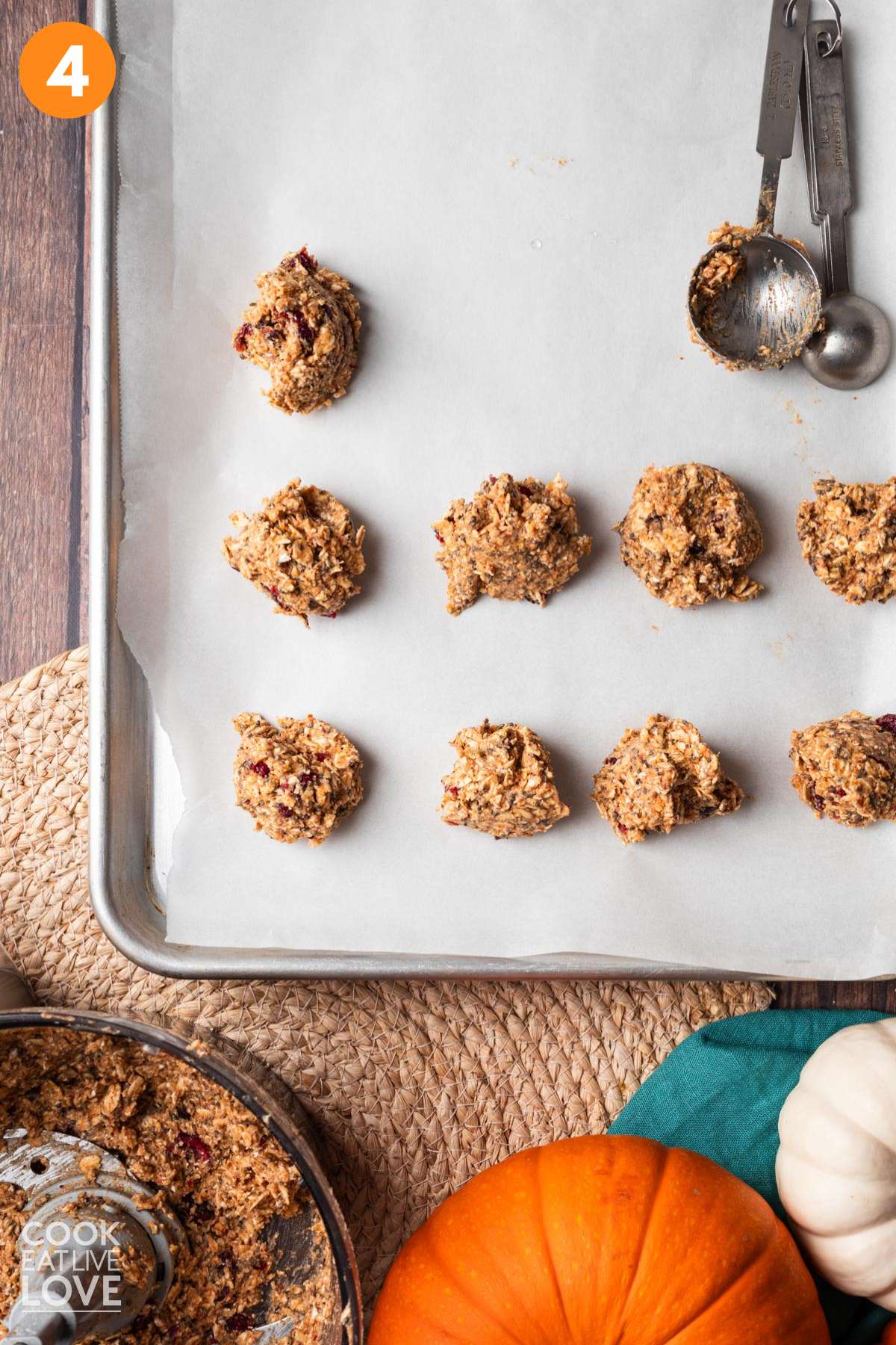 Dough scoops on a parchment lined baking tray with a tablespoon measure to the side.